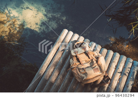 Backpack of traveller on wooden pier near summer tranquil lake. View from above. 96430294