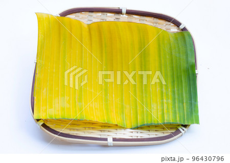 Yellow green banana leaf in bamboo weave plate on white background. 96430796
