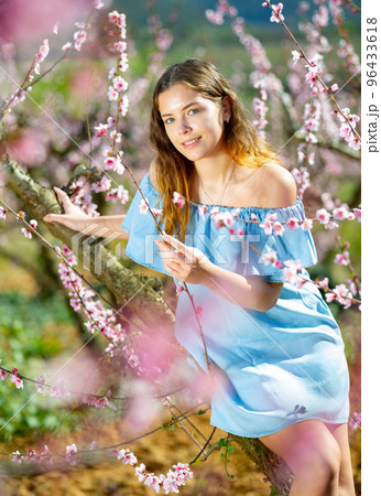 Portrait of young smiling woman in a garden with blooming peach trees 96433618