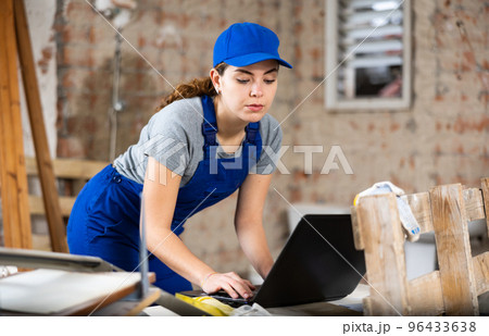 Woman construction worker using laptop in apartment Woman construction worker using laptop in apartment 96433638