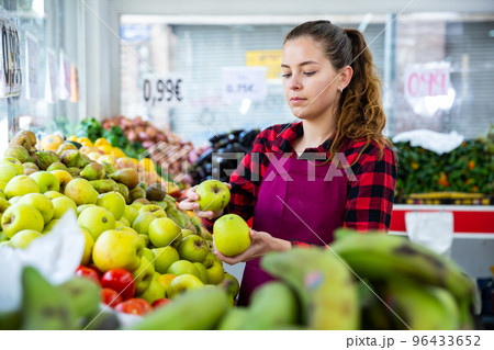 Young saleswoman puts apples on the counter Young saleswoman puts apples on the counter 96433652
