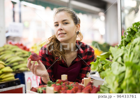 Portrait of a seller girl at the counter holding strawberries 96433761