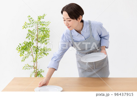 食卓にお皿をならべる女性 食卓にお皿をならべる女性 96437915
