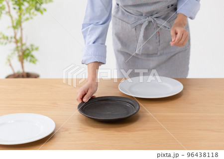 食卓にお皿をならべる女性の写真素材 96438118