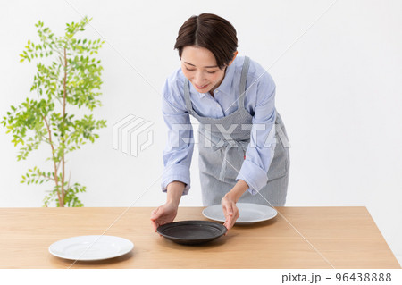 食卓にお皿をならべる女性 96438888