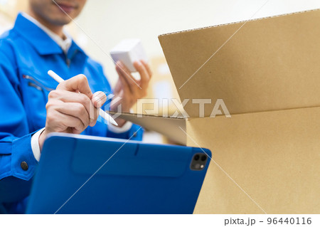 荷物を検品してタブレットPCでチェックする男性 96440116
