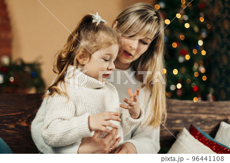 Mom and daughter in casual clothes play and hug against the background of a Christmas tree. Christmas and New Year, Christmas holidays, Christmas time. Childhood, motherhood, time together Mom and daughter in casual clothes play and hug against the background of a Christmas tree. Christmas and New Year, Christmas holidays, Christmas time. Childhood, motherhood, time together 96441108
