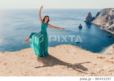 Side view a Young beautiful sensual woman with black hair in a long mint dress posing on a beach with calm sea bokeh lights on sunny day. Girl on the nature on blue sky background. Fashion photo Side view a Young beautiful sensual woman with black hair in a long mint dress posing on a beach with calm sea bokeh lights on sunny day. Girl on the nature on blue sky background. Fashion photo 96443297