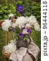 Bouquet of bearded irises and white peonies on a chair. 96444118