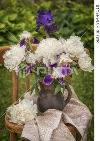 Bouquet of bearded irises and white peonies on a chair. 96444118