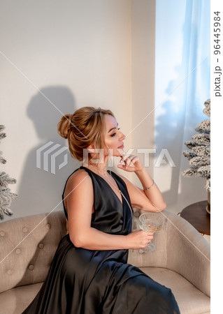 Portrait of a wealthy mature woman with evening make-up and hairstyle posing in a black dress on the background of the Christmas room. Luxurious lifestyle. Christmas holidays concept 96445984