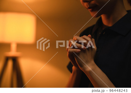 woman hand praying with magic light that flows through on orange bokeh background. woman hand praying with magic light that flows through on orange bokeh background. 96448243