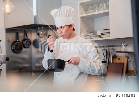 厨房で味見をする男性シェフ 厨房で味見をする男性シェフ 96448281