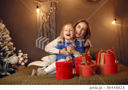 People reparing for Christmas. Mother playing with her daughter. Family is resting in a festive room. Child in a blue sweater. People reparing for Christmas. Mother playing with her daughter. Family is resting in a festive room. Child in a blue sweater. 96448628