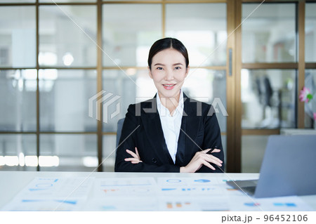 Portrait of a thoughtful Asian businesswoman looking at financial statements and making marketing plans using a computer on her desk. Portrait of a thoughtful Asian businesswoman looking at financial statements and making marketing plans using a computer on her desk. 96452106