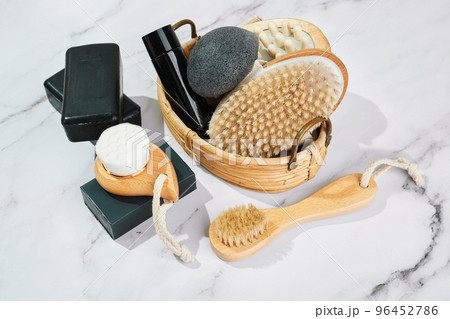Three pieces of black charcoal soap, Konjac sponge, beauty care products, candles and brushes for washing and massage on marble background Three pieces of black charcoal soap, Konjac sponge, beauty care products, candles and brushes for washing and massage on marble background 96452786