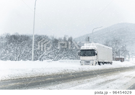 Big commercial semi-trailer truck trapped in snow drift on closed highway road at heavy snow storm blizzard cold winter day. Cargo vehicle stuck on freeway at bad weather conditions frosty snowfall Big commercial semi-trailer truck trapped in snow drift on closed highway road at heavy snow storm blizzard cold winter day. Cargo vehicle stuck on freeway at bad weather conditions frosty snowfall 96454029