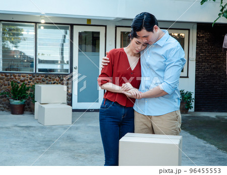 Man comforting his wife and woman hugging her husband and cry in front of the house and full of cardboard boxes during the transport in move out day, moving home concept Man comforting his wife and woman hugging her husband and cry in front of the house and full of cardboard boxes during the transport in move out day, moving home concept 96455553