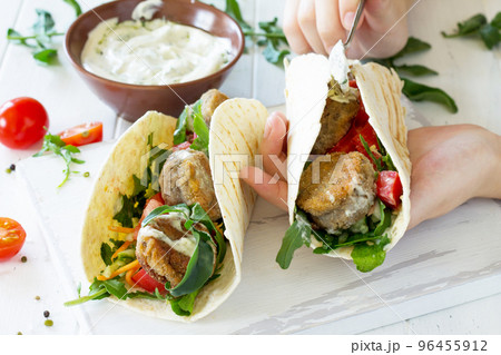 Arabic cuisine. Concept of vegetarian food. Delicious fresh homemade vegetarian tortilla with falafel on a wooden kitchen table. Cooking. Arabic cuisine. Concept of vegetarian food. Delicious fresh homemade vegetarian tortilla with falafel on a wooden kitchen table. Cooking. 96455912