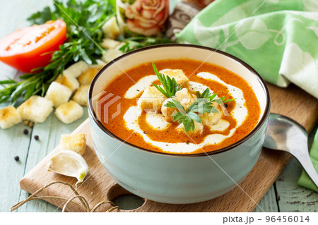 Diet menu. Puree soup tomato with croutons and cream in a bowl on a kitchen wooden table. The concept of healthy eating. 96456014