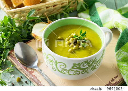 Diet menu. Puree soup with green pea in a bowl on a kitchen wooden table. The concept of healthy eating. 96456024