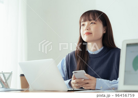 オフィスでスマホ操作する若い女性 96456759
