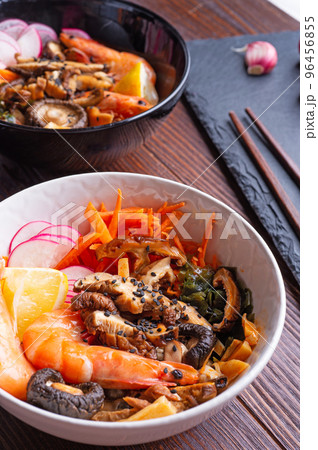 miso soup with mussels, shrimps , shiitake mushrooms and vegatables. served at dark brown wooden table. flat lay 96456855