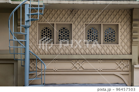 Blue metal spiral staircase with iron railing lead down in front of Beautiful architecture external wall. Blue metal spiral staircase with iron railing lead down in front of Beautiful architecture external wall. 96457503