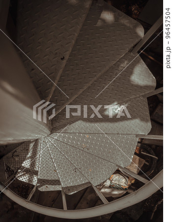 Top view of metal steps of outside spiral staircase with sunlight and shadow on surface. Top view of metal steps of outside spiral staircase with sunlight and shadow on surface. 96457504