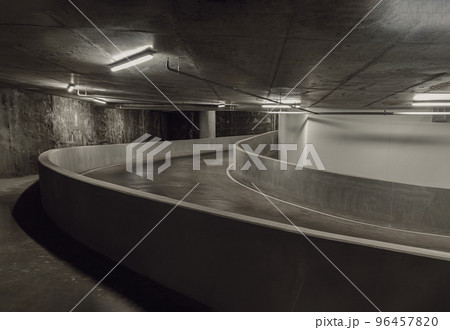 Way down to underground car parking. Perspective view of Curving shaped ramp of the basement made of concrete. Way down to underground car parking. Perspective view of Curving shaped ramp of the basement made of concrete. 96457820