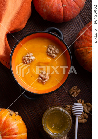 baked pumpkin cream coup with, walnuts ,  coconut milk and natural honey served in nice bowl. served at wooden brown table with ripe orange  pumkins. flat lay. healthy life concept 96459002