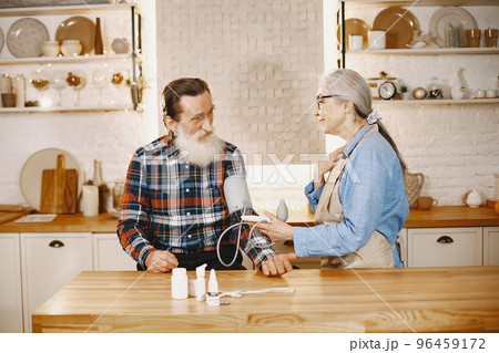 Old couple in a kitchen. Woman in a blue shirt and aprone. 96459172