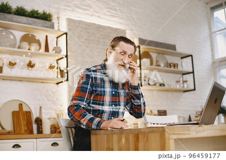Old man with laptop. Grandfather sitting in a Christmas decorations. Man with mobile phone. 96459177