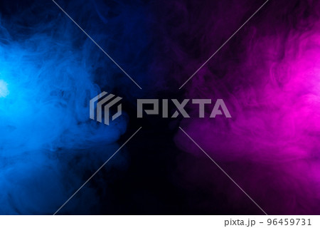 Clouds of colorful smoke in blue and purple neon light swirling on black table background  96459731