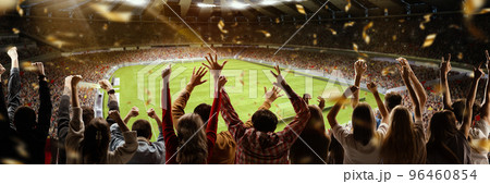 Victory. Back view of football soccer fans cheering their team with colorful scarfs at crowded stadium at evening time. Concept of sport, cup, world, team, event, competition 96460854