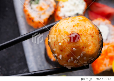 baked sushi roll holding by sticks. sushi rolls served at grey  tray. flat lay. close up 96460948