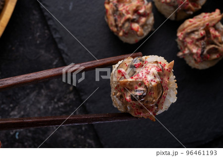 sushi roll  with shiitake mushrooms  holding in sticks served  at black dish at black table. 96461193