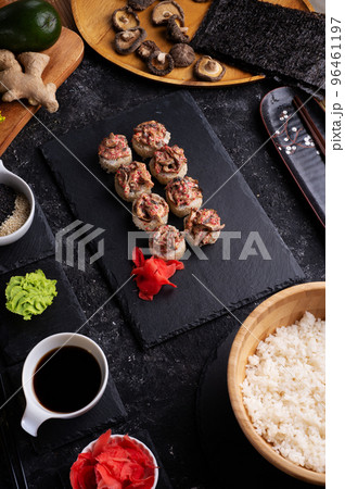 sushi roll  with shiitake mushrooms  holding in sticks served  at black dish at black table. 96461197