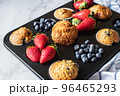 Assorted blueberry and strawberry muffins in a baking tin. Close up. 96465293
