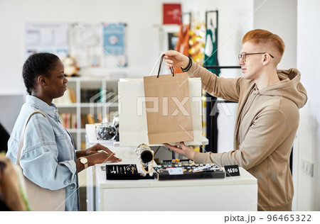 Male store manager handing paper bags to customer Male store manager handing paper bags to customer 96465322