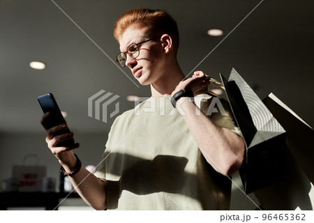 Man using smartphone while enjoying shopping at thrift store Man using smartphone while enjoying shopping at thrift store 96465362