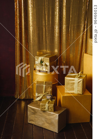 Stack of colorful gift boxes in golden wrapping paper with ribbons 96466013