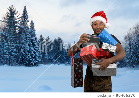 man holding gift boxes for christmas in the snow winter landscape and wearing red santa hat outside man holding gift boxes for christmas in the snow winter landscape and wearing red santa hat outside 96466270
