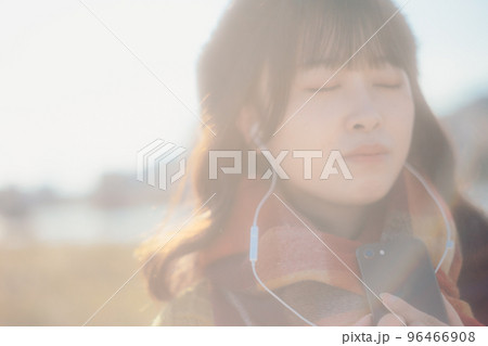 河川敷に音楽を聴きながら佇む若い女性の写真 河川敷に音楽を聴きながら佇む若い女性の写真 96466908
