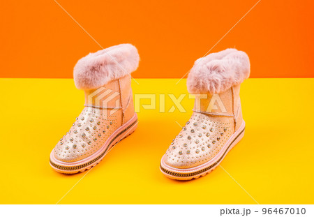 pair of fashionable winter beige ugg boots on yellow background, new pair pair of fashionable winter beige ugg boots on yellow background, new pair 96467010