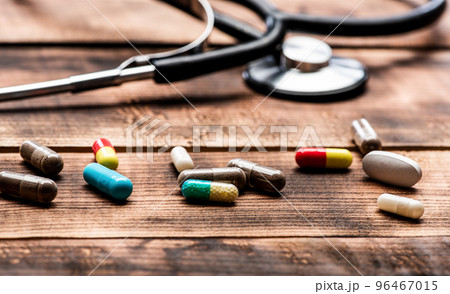 Assorted capsules pharmaceutical drugs and stethoscope wooden background, medical care Assorted capsules pharmaceutical drugs and stethoscope wooden background, medical care 96467015