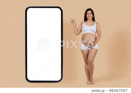 Mobile Offer. Smiling Pregnant Woman Pointing Aside At Big Blank Smartphone Mobile Offer. Smiling Pregnant Woman Pointing Aside At Big Blank Smartphone 96467097