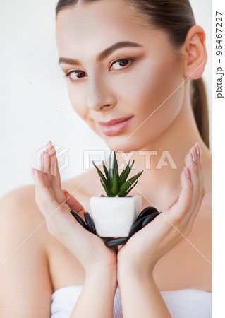Woman with perfect skin holds a green plant in her hands. Woman with perfect skin holds a green plant in her hands. 96467227