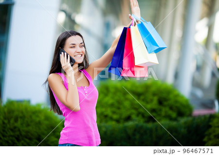 Woman walk near shopping mall with colored packs 96467571