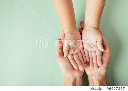 Closeup top view family hands stack palms studio shot isolated on green background, parents and kid holding empty free space on hand together, Gesture sign of support and love, Family and parents day 96467827